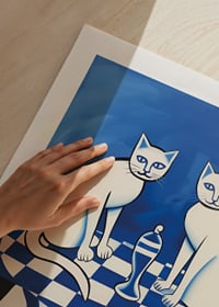 Två katter sitter på ett blå-och-vitt schackrutigt bord-9