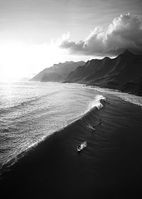 Afiș alb-negru cu surferi călărind valuri puternice pe o coastă dramatică-3