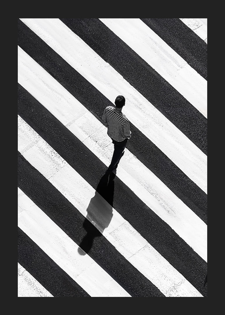A man walks across a striped crosswalk in black and white-12