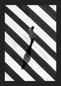 En man promenerar över ett randigt övergångsställe i svartvitt-5