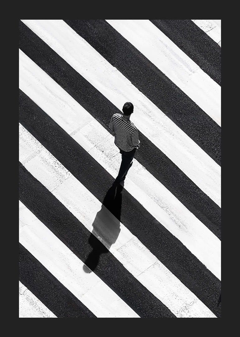 En man promenerar över ett randigt övergångsställe i svartvitt-12