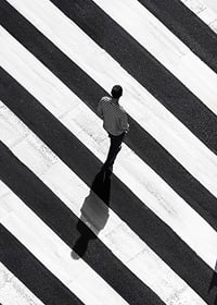 A man walks across a striped crosswalk in black and white-7