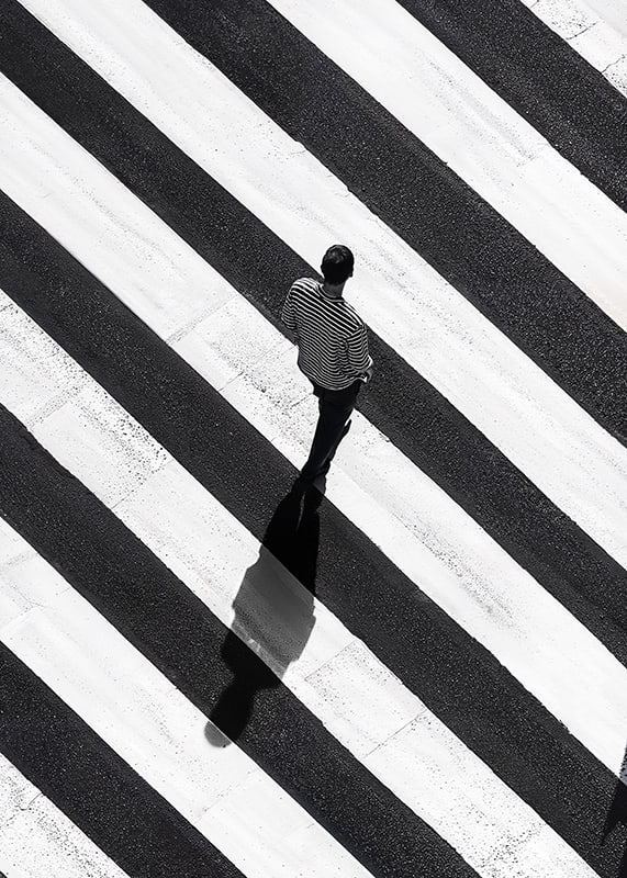 A man walks across a striped crosswalk in black and white-12