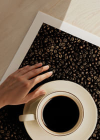 O ceașcă albă perfectă înconjurată de boabe de cafea închise la culoare.-5