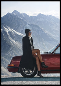 A stylish woman leans against a car with mountains in the background.-6