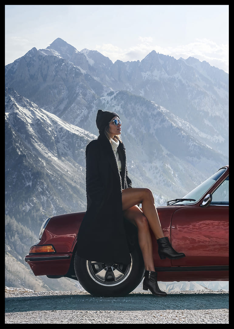 A stylish woman leans against a car with mountains in the background.-12
