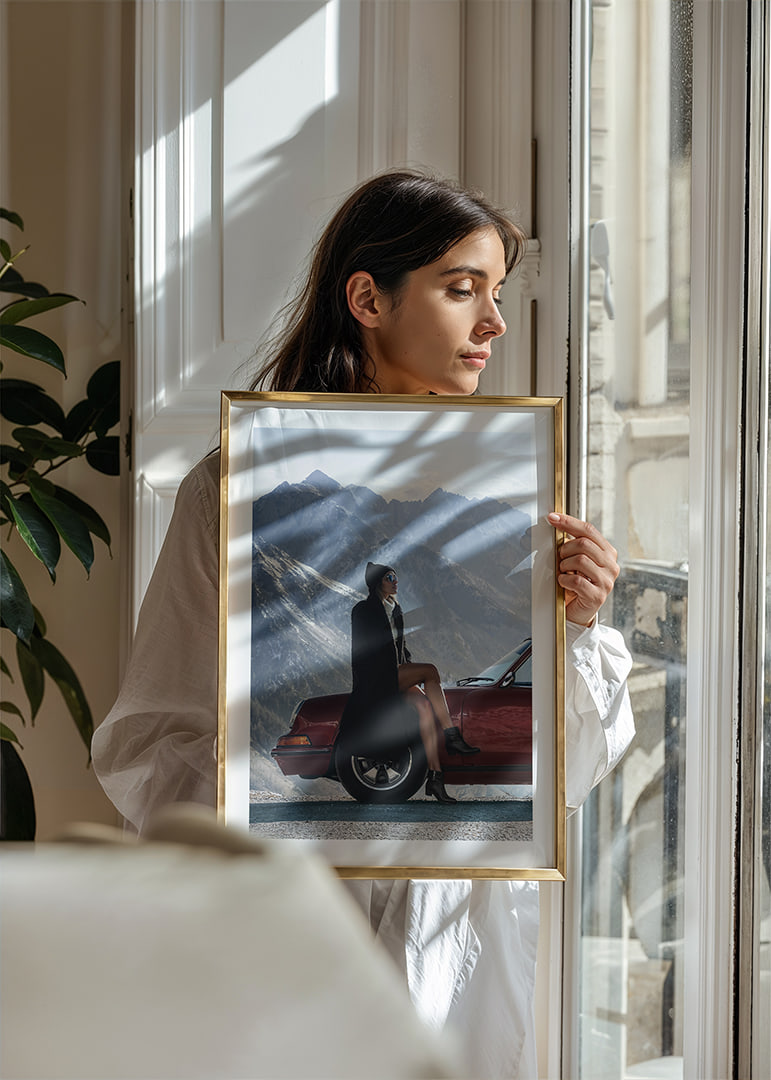 A stylish woman leans against a car with mountains in the background.-12