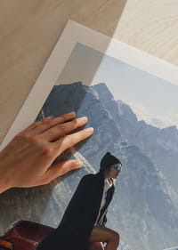 A stylish woman leans against a car with mountains in the background.-5