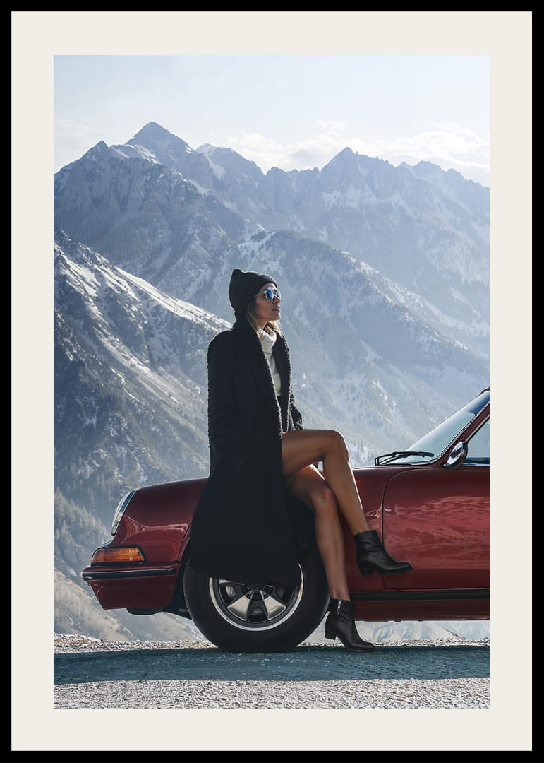 Une femme élégante est appuyée contre une voiture, avec des montagnes en arrière-plan.-12
