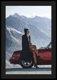 A stylish woman leans against a car with mountains in the background.-4