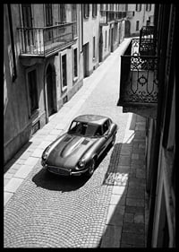 En klassisk Jaguar E-Type majestätiskt på en solbelyst stenlagd gata.-6