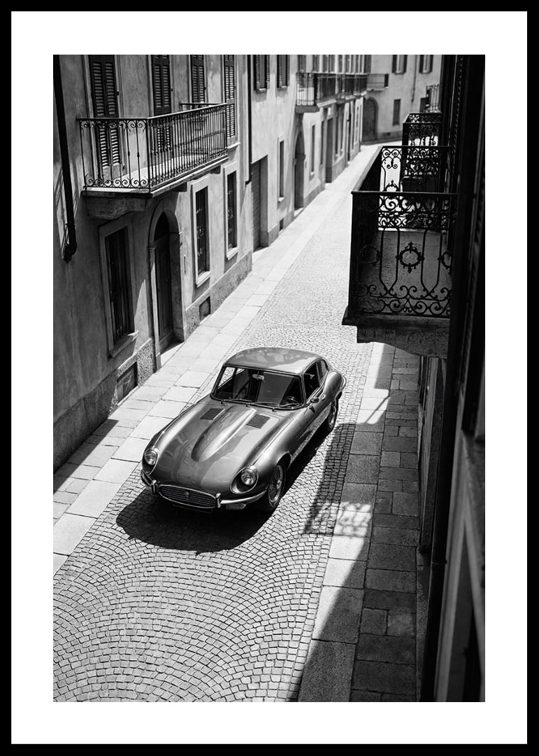 En klassisk Jaguar E-Type majestätiskt på en solbelyst stenlagd gata.-12