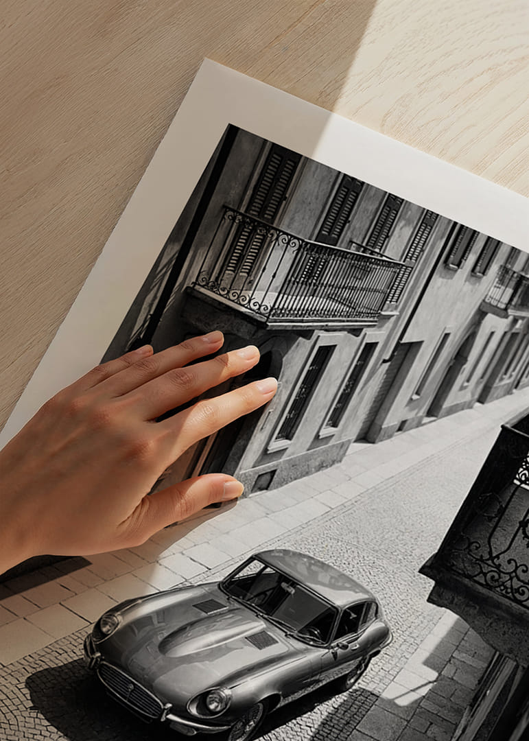 A classic Jaguar E-Type majestically stands on a sunlit cobblestone street.-12