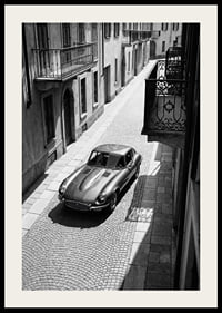 En klassisk Jaguar E-Type majestätiskt på en solbelyst stenlagd gata.-2
