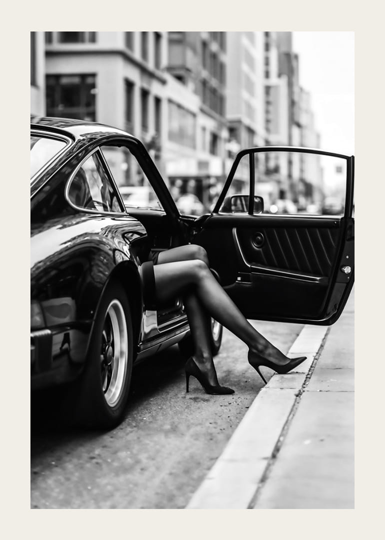 Elegant legs extend from a Porsche 911 in an urban setting.-12