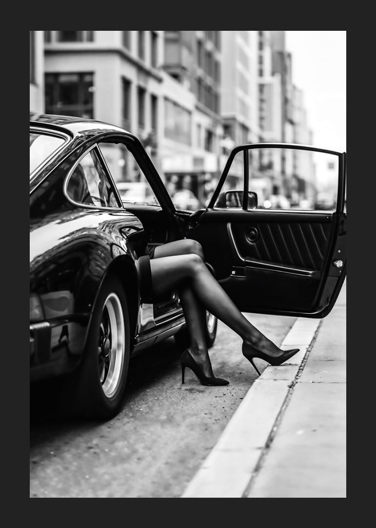 Elegant legs extend from a Porsche 911 in an urban setting.-12