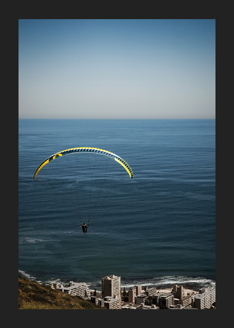 A paraglider soars majestically over the sea and the city.-12
