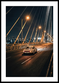 Porsche 911 clasic pe un pod iluminat spre oraș noaptea.-0