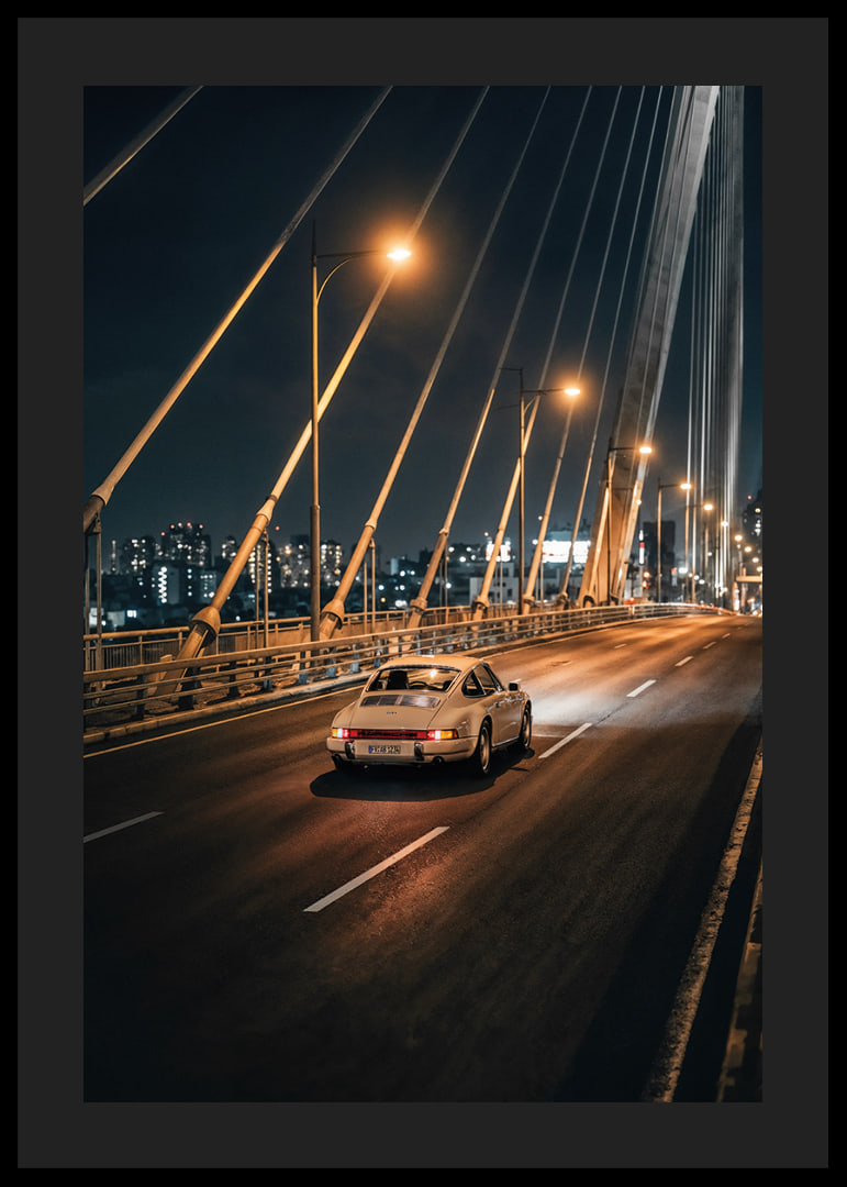 Porsche 911 clasic pe un pod iluminat spre oraș noaptea.-12