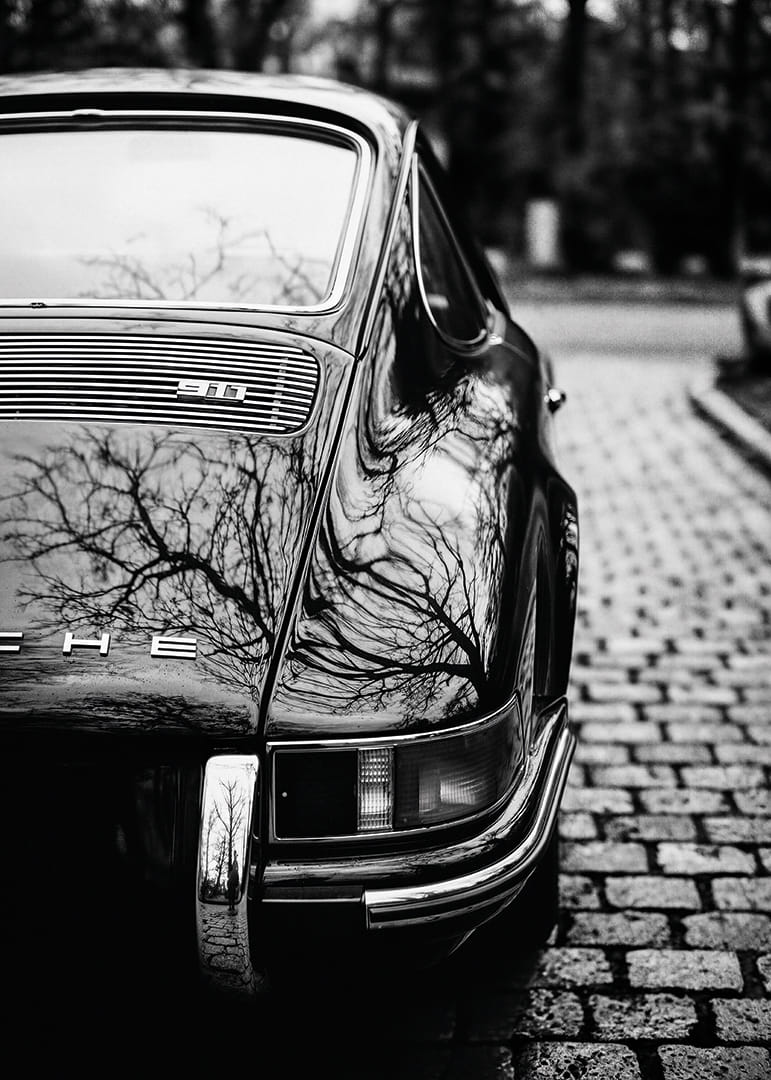 Klasisks Porsche 911 rada nostalģisku sajūtu uz bruģakmens ielas.-12