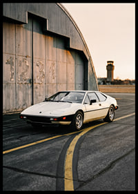Elegant classic Lotus Esprit in front of industrial building at sunset.-6