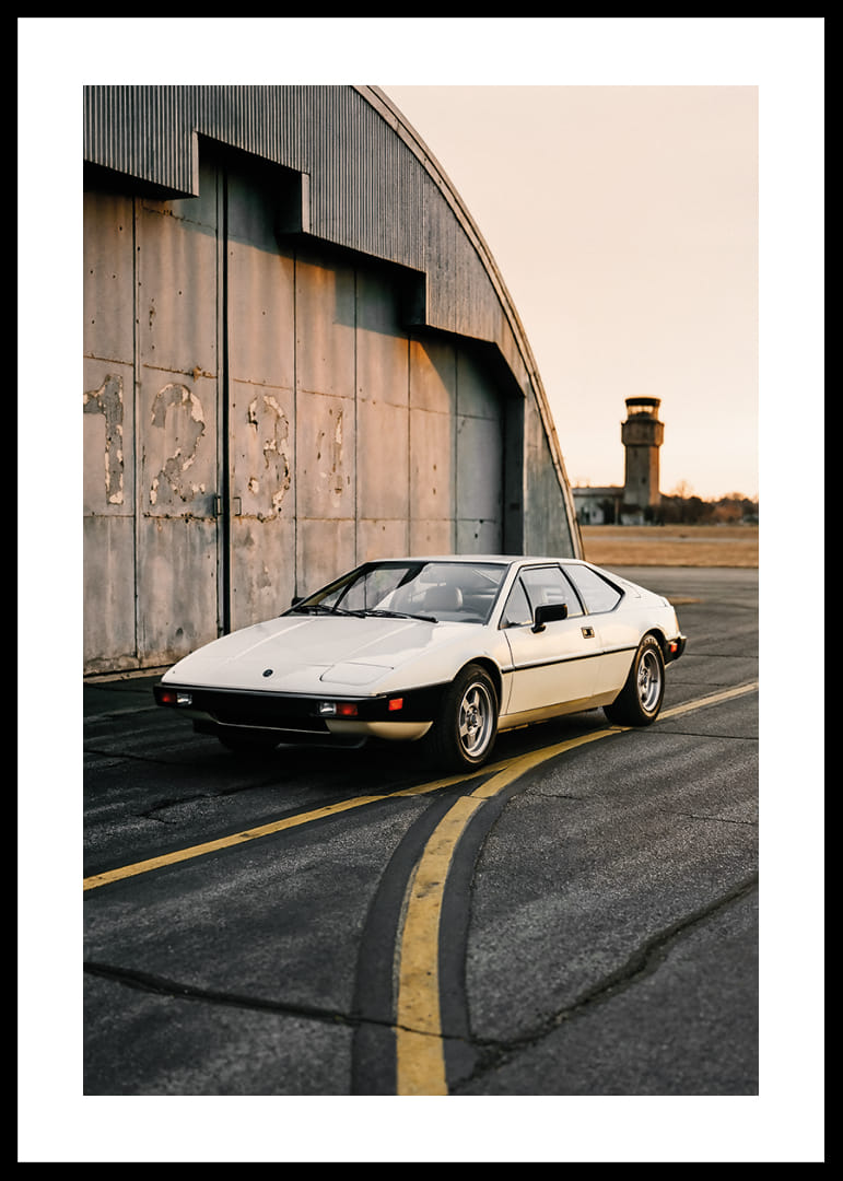 Elegants klasiskais Lotus Esprit rūpniecības ēkas priekšā saulrietā.-12