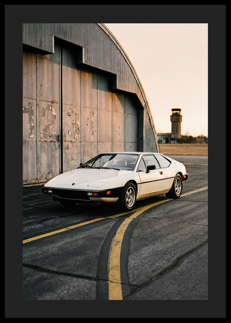 Elegant classic Lotus Esprit in front of industrial building at sunset.-12