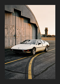 Elegant classic Lotus Esprit in front of industrial building at sunset.-5
