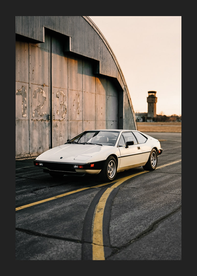 Elegant classic Lotus Esprit in front of industrial building at sunset.-12