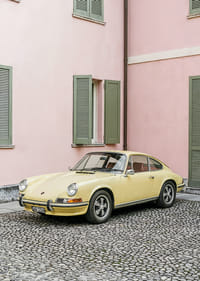 Burvīgs pasteļdzeltens Porsche 911 rozā sienas priekšā rada retro sajūtu.-3