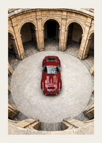 En röd klassisk Ferrari 250 GTO  i en majestätisk innergård.-3