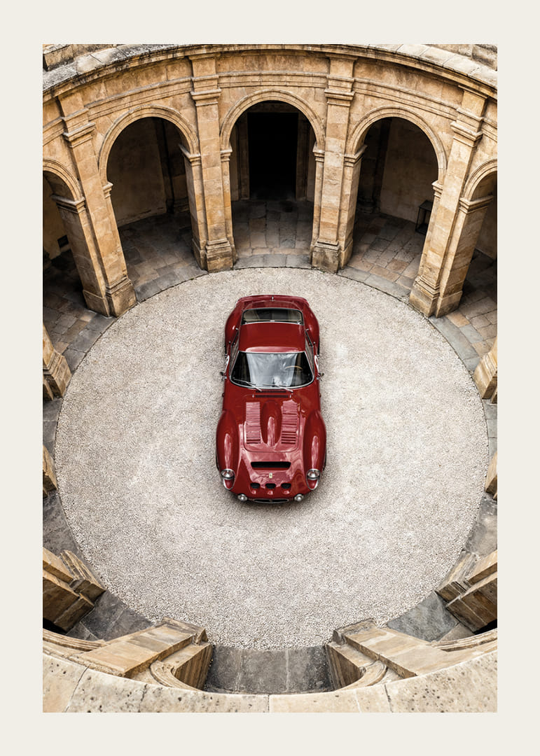 En röd klassisk Ferrari 250 GTO  i en majestätisk innergård.-12