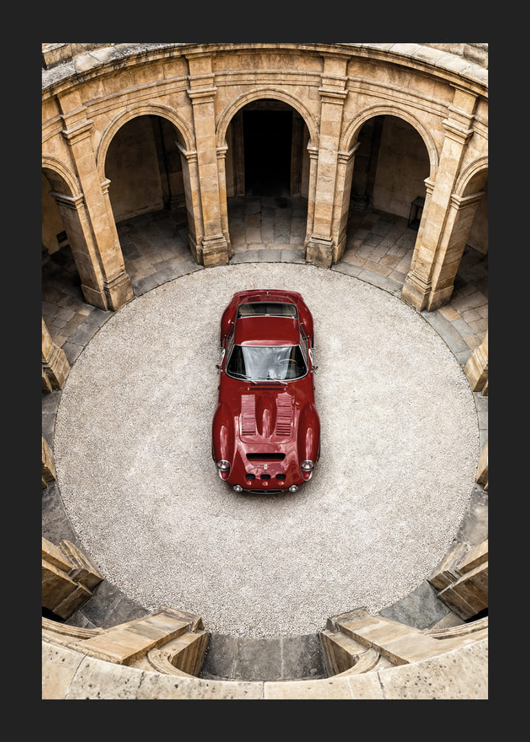 En röd klassisk Ferrari 250 GTO  i en majestätisk innergård.-12