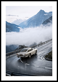 En klassisk Aston Martin DB5 färdas genom dimmiga berg på en slingrande väg.-0