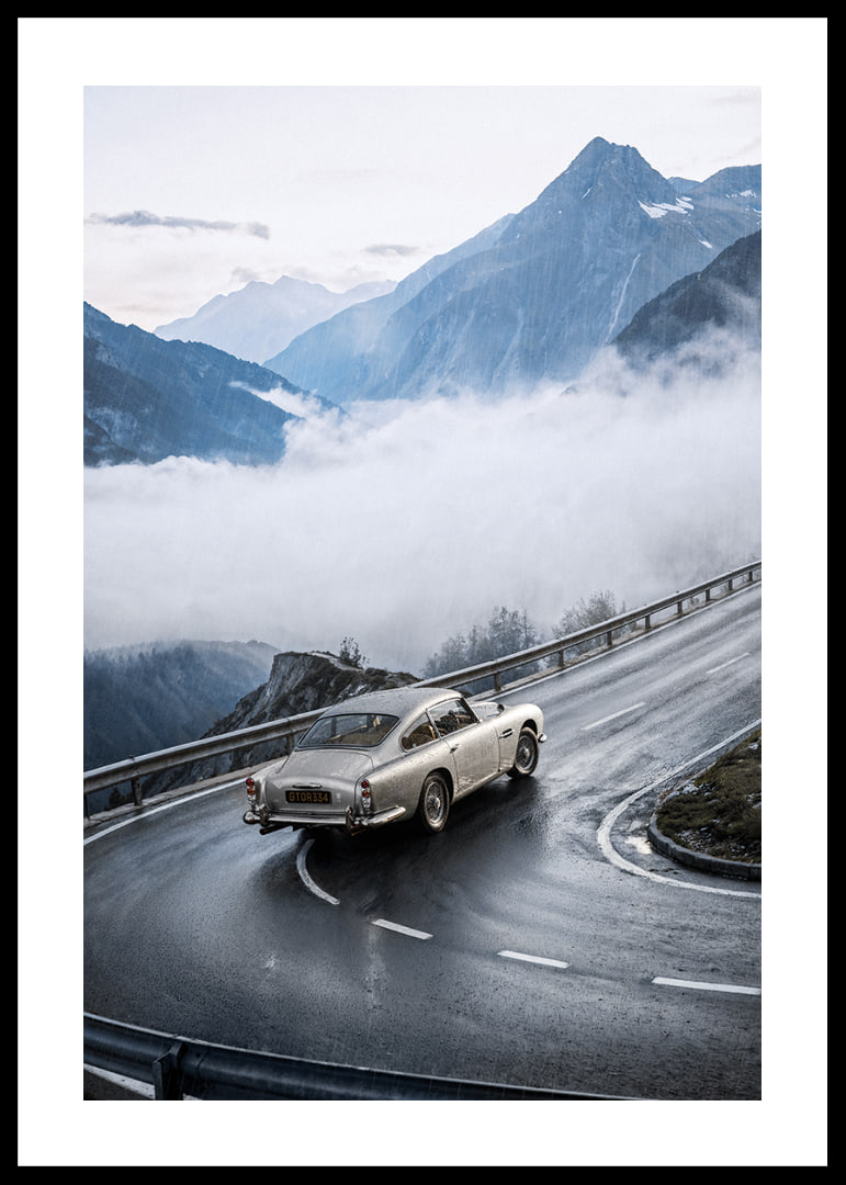 En klassisk Aston Martin DB5 färdas genom dimmiga berg på en slingrande väg.-12