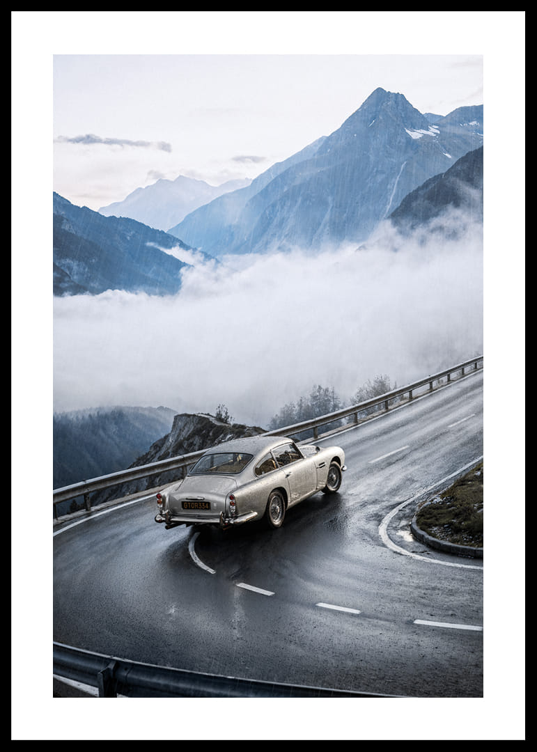 Une Aston Martin DB5 classique traverse des montagnes brumeuses sur une route sinueuse.-12