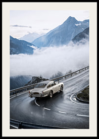 En klassisk Aston Martin DB5 färdas genom dimmiga berg på en slingrande väg.-2