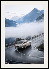 En klassisk Aston Martin DB5 färdas genom dimmiga berg på en slingrande väg.-2