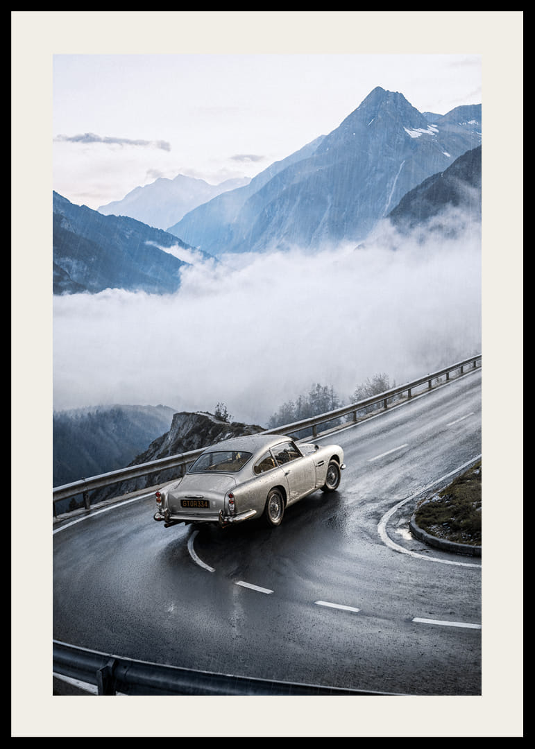 En klassisk Aston Martin DB5 färdas genom dimmiga berg på en slingrande väg.-12