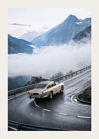 En klassisk Aston Martin DB5 färdas genom dimmiga berg på en slingrande väg.-3