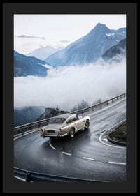 En klassisk Aston Martin DB5 färdas genom dimmiga berg på en slingrande väg.-4