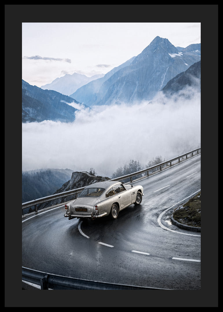 En klassisk Aston Martin DB5 färdas genom dimmiga berg på en slingrande väg.-12