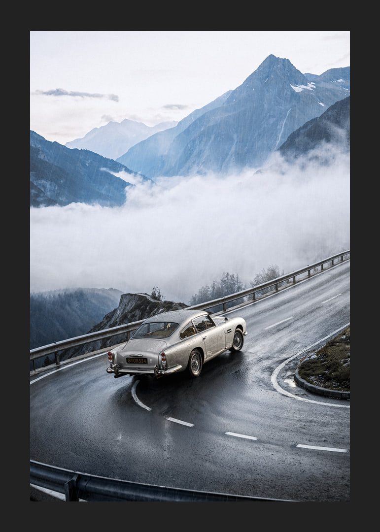 En klassisk Aston Martin DB5 färdas genom dimmiga berg på en slingrande väg.-12