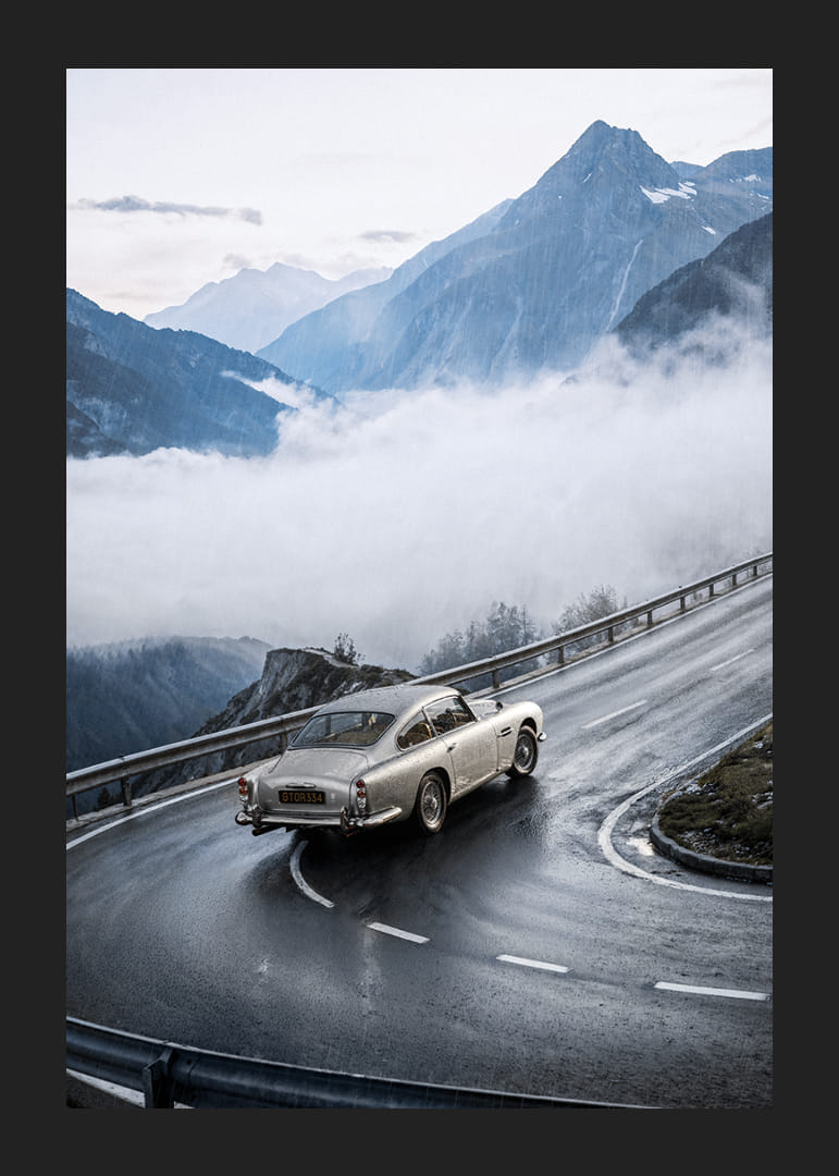 En klassisk Aston Martin DB5 färdas genom dimmiga berg på en slingrande väg.-12