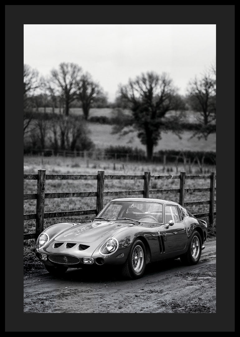 En klassisk Ferrari 250 GTO står ståtlig på en grusväg omgiven av träd.-12