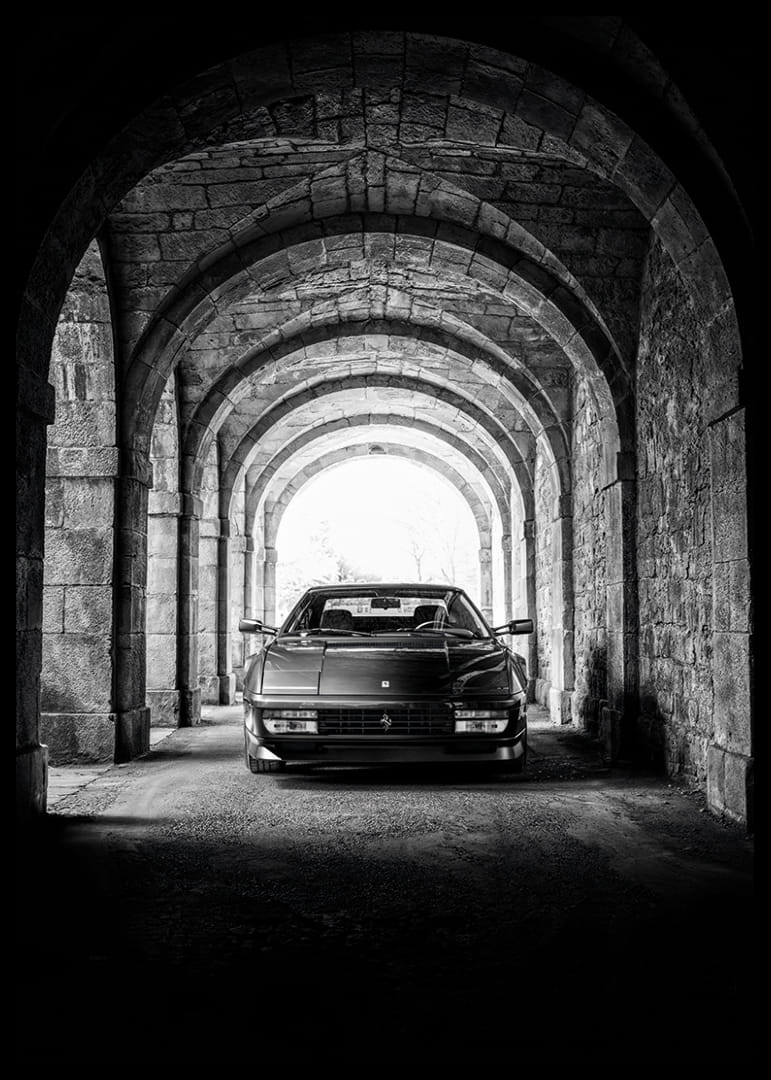 En klassisk Ferrari Testarossa genom en stentäckt valvpassage.-12