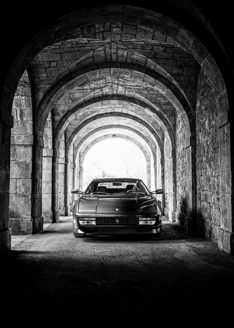 En klassisk Ferrari Testarossa genom en stentäckt valvpassage.-12
