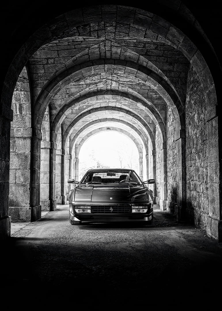 En klassisk Ferrari Testarossa genom en stentäckt valvpassage.-12