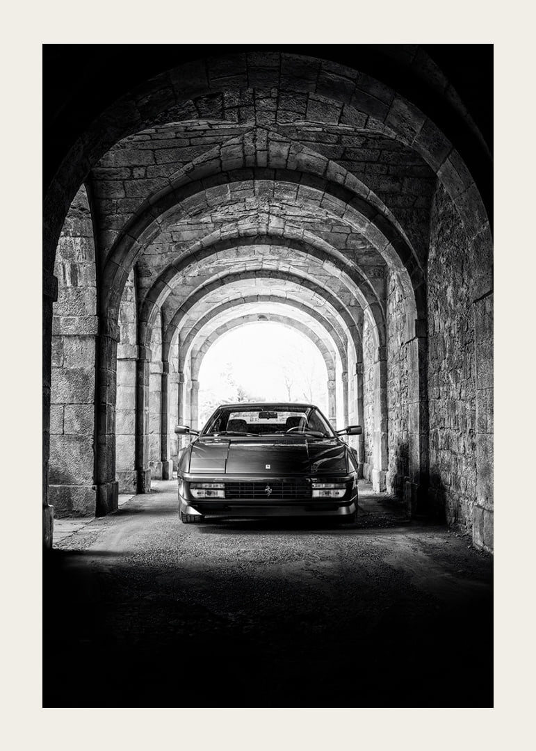 En klassisk Ferrari Testarossa genom en stentäckt valvpassage.-12
