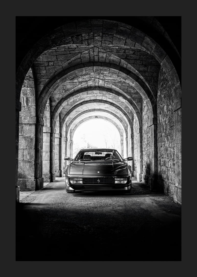 En klassisk Ferrari Testarossa genom en stentäckt valvpassage.-12